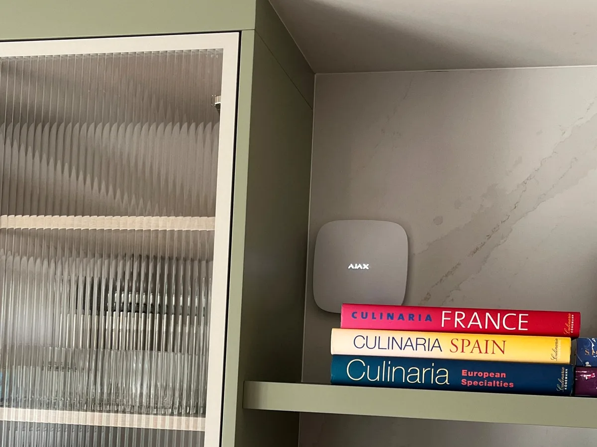 Discreet Ajax alarm hardware integrated into a modern kitchen shelf area