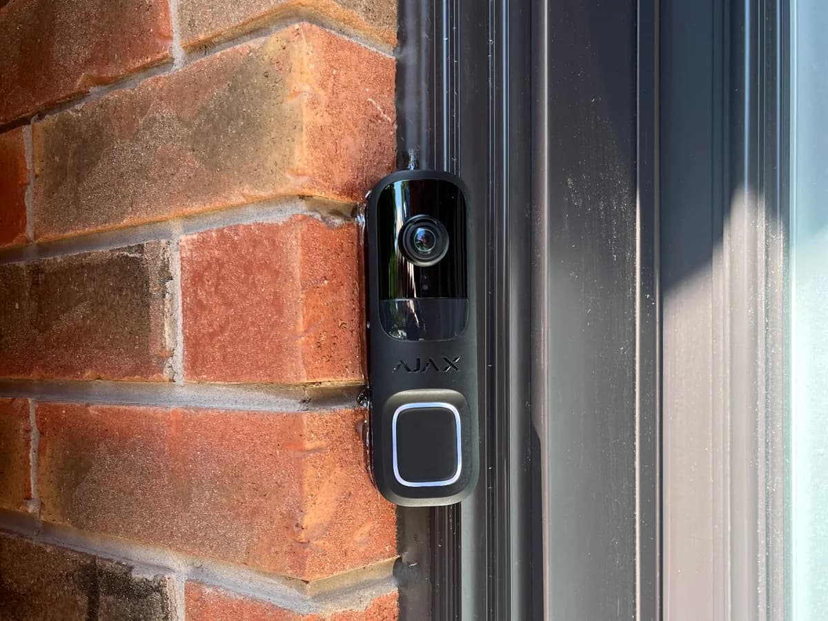 Ajax video doorbell installed discreetly beside a brick front entry