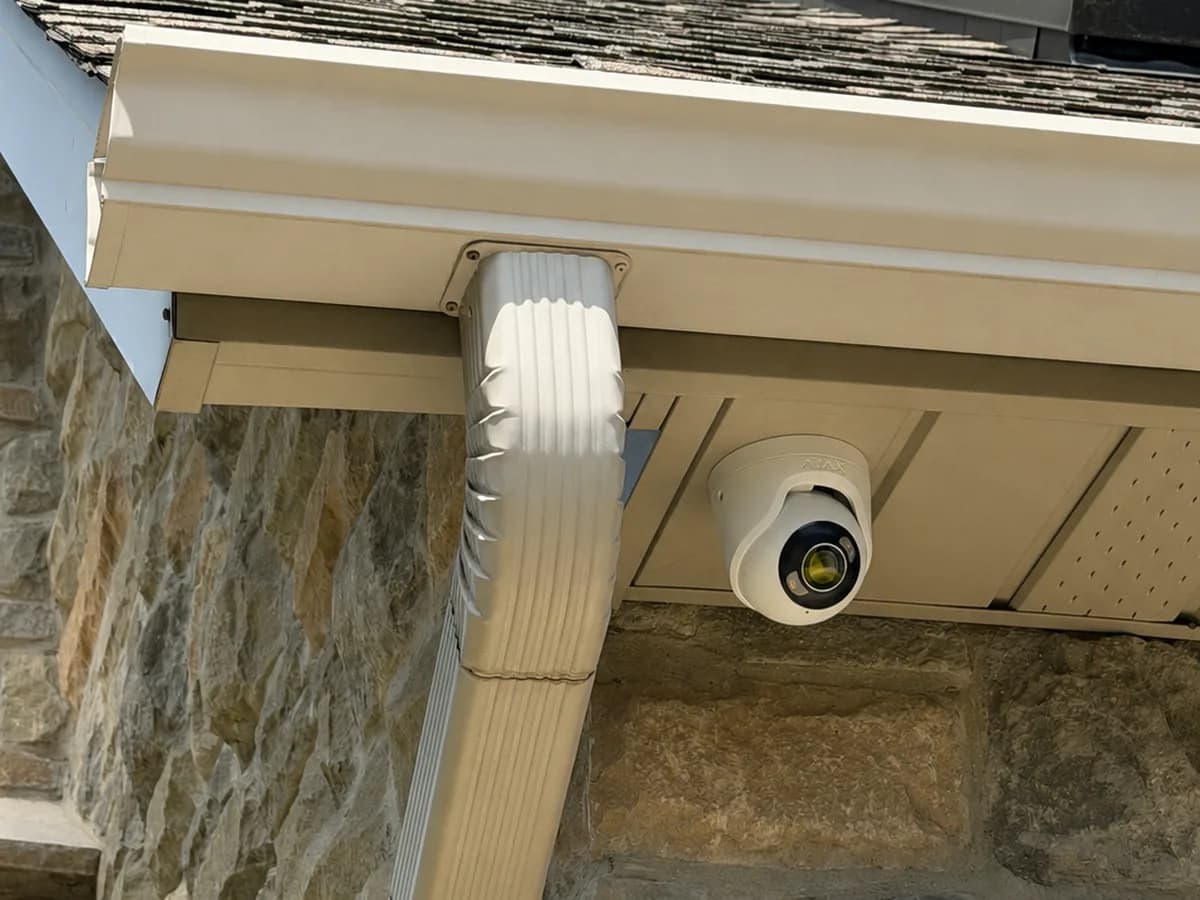 Ajax security camera installed on a stone home soffit for exterior property coverage.